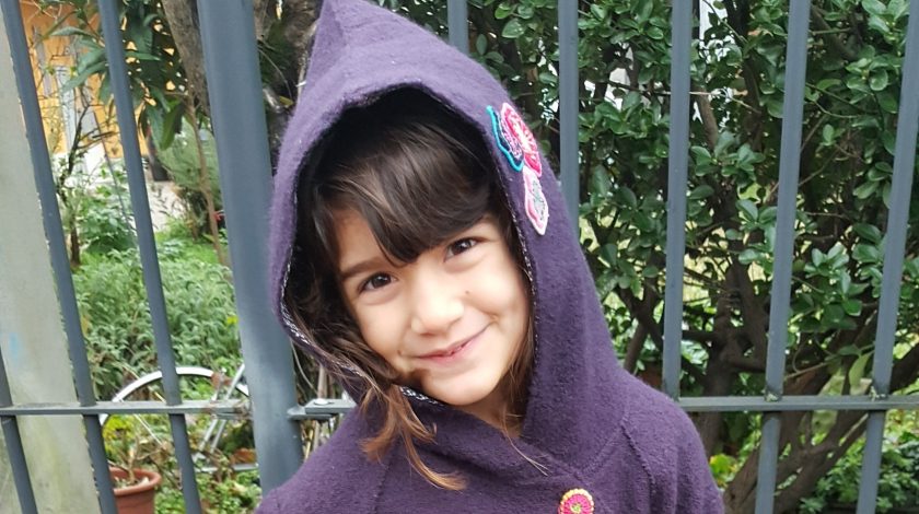 bambina di 5 anni con cappotto viola e con il cappuccio in testa